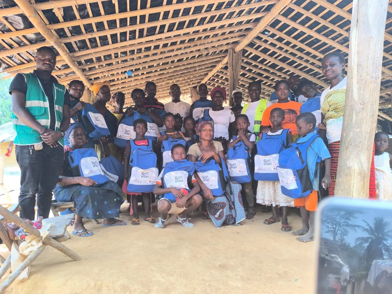 Enfants et familles d'un village tenant leurs sacs à dos Ritter Sport lors d'une distribution