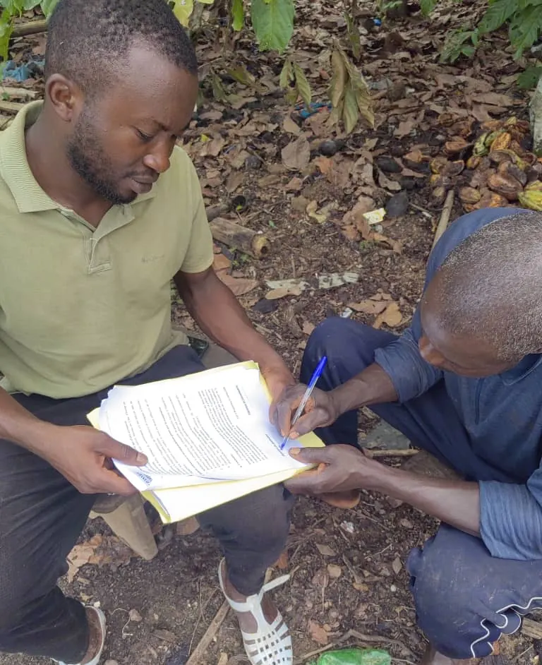 Producteur signant un document remis par un technicien de la coopérative, dans un verger